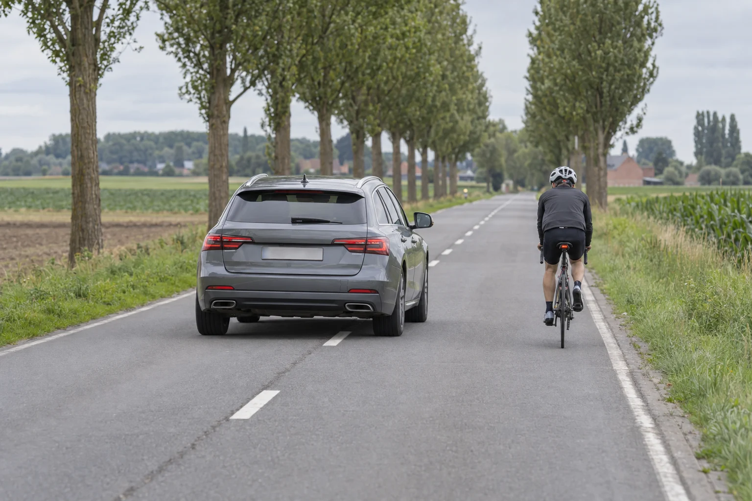 Car overtaking a cyclist with a wide gap on a Belgian country road.