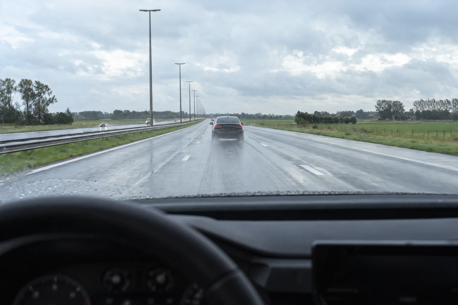 View from inside the car on a Belgian motorway, a car ahead at a safe distance.