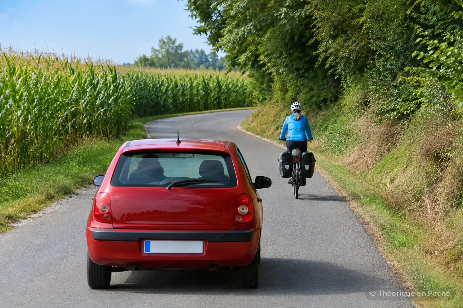 Voiture roulant derrière un cycliste à l'approche d'un virage sans visibilité